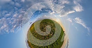 Green little planet fast revolves among beautiful blue sky with white clouds. tiny planet transformation with curvature of space.