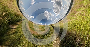 Green little planet revolves among clear blue sky and white clouds. Little planet transformation with curvature of space. loop rot