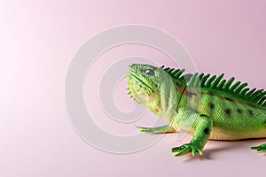 Green lizard toy on pastel pink background. Minimal art concept