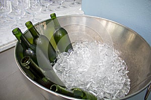 Green long neck water bottles in a metal stainless steel bowl with ice cubes