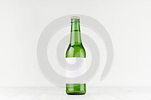 Green longneck beer bottle 330ml with blank white label on white wooden board, mock up.