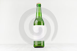 Green longneck beer bottle 500ml with blank white label on white wooden board, mock up.