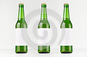 Green longneck beer bottles 500ml with blank white label on white wooden board, mock up.