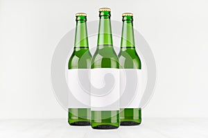 Green longneck beer bottles 500ml with blank white label on white wooden board, mock up.