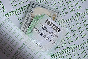 Green lottery tickets and US money bills on blank with numbers for playing lottery