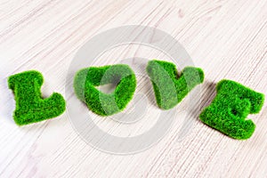 Green love wording on wooden floor, made from artificial grass