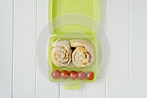 Green lunchbox with scrolls and tomato