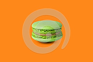 Green macaron isolated on orange background. with a shadow