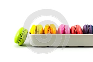 Green macarons are isolated on a white floor and multicolored macarons are housed in white ceramic vessels, space for text