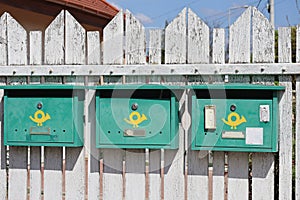 Green mailboxes on the white fence