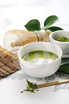 Green matcha tea drink and tea accessories on white background