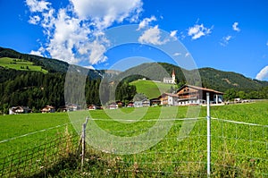 Green meadow and alpine houses in Strassen village, Austria