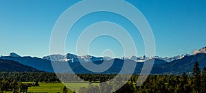 Green meadow field, snow covered mountain range. European Alps at bad toelz Brauneck. Isartal Valley