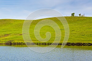 Green meadow with lake, hills and sky