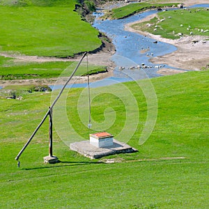 Green meadow, river and well Crane