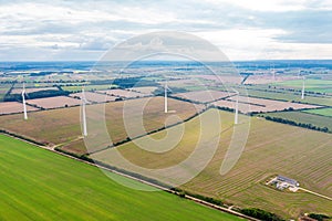 Green meadow with wind turbines generating electricity, summer landscape with blue sky, alternative energy sources