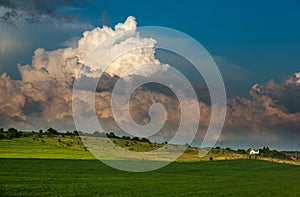 Green meadows landscape in countryside hills on impressive huge clouds in sky, beauty in nature