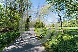 Green meadows and a walking trail and the Molenbeek creek at the Boudewijn city park on a Sunny day in spring