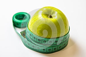 Green measuring tape over green apple. Diet and Healthy life, loss weight concept. Isolated. White background