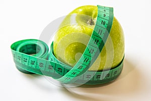 Green measuring tape over green apple. Diet and Healthy life, loss weight concept. Isolated. White background