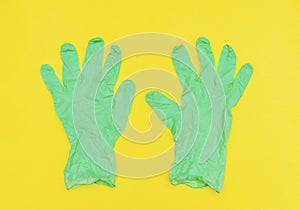 Green medical protective surgical rubber gloves on yellow background