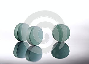 Green medicine pills on white background.