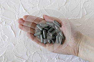 Green medicines or supplements, chlorophyll or spirulina capsules in a woman& x27;s hand