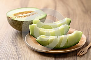 Green melon fruit on wooden plate