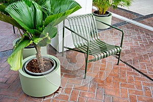 Green metal chair with planting along a walkway. Rest area along pedestrain way