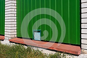 Green metal corrugated fence with brick pillars.