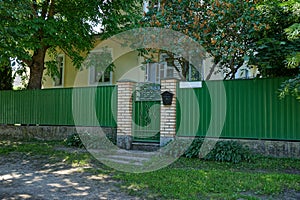 A green metal fence and a closed door on the street near the road