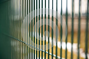 Green metal fence from rods on the street