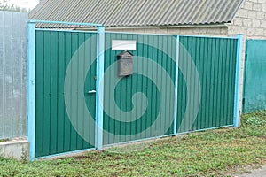 Green metal gate and closed door with part  fence