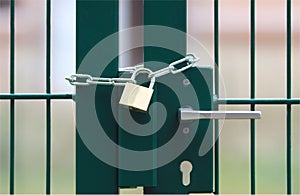 Green metal gate, locked with chain and padlock