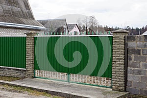 Green metal gate and part of a long fence in the street