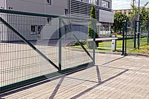 Green metal gate and barrier on the sidewalk in front of the industrial building