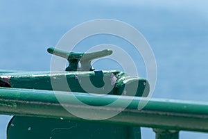 Green metal rope tie down on the deck area of a ferry
