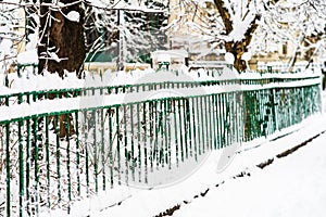 Green metallic fence with snow. Metal fence in winter covered with snow. .Snowy environment in the morning