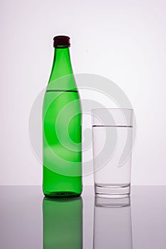 green mineral water bottle with glass on white background