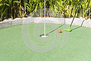 Green Mini Golf Club Putting an Orange Ball