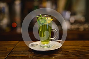 Green mint tea with lemon on bar counter.