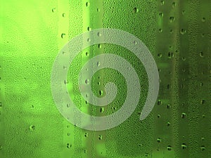 Green misted glass with water droplets and uneven lighting. Abstract background.