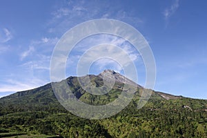 A green montain under a blue sky with white clouds