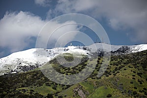 A green mountain with a snow on top