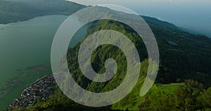 Green mountain with trees under cloudy sky seen from above