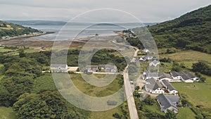 Green mountain valley village aerial. Scottish nature landscape of town at sea lake, castle ruins