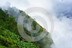 Green mountains cliff and low white clouds