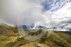 Green mountains panoramic view on blue sky with white clouds copy space background on bright sunny day. Tourism and traveling