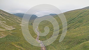 Green mountains path aerial. Narrow way from hill to cloudy peak. Cinematic nobody nature landscape