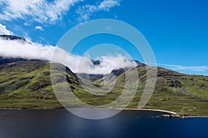 Green mountains under blue cloudy sky on a sunny warm day and lake with blue water. Nature scene in Connemara, Ireland. Irish